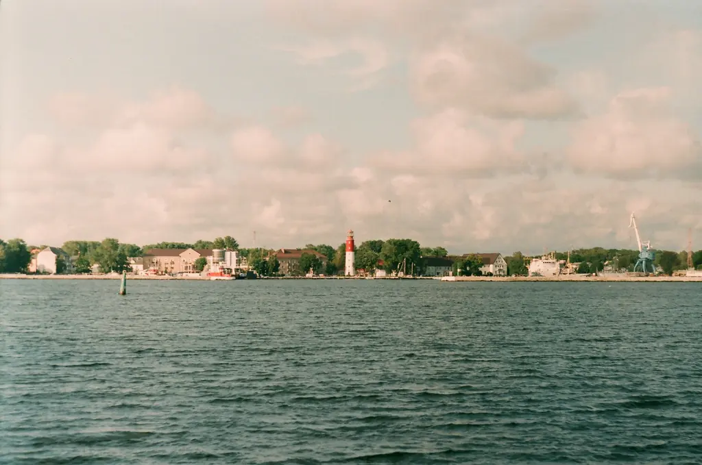 Blick über die Kieler Förde auf das gegenüberliegende Ufer unter rosa Wolken.