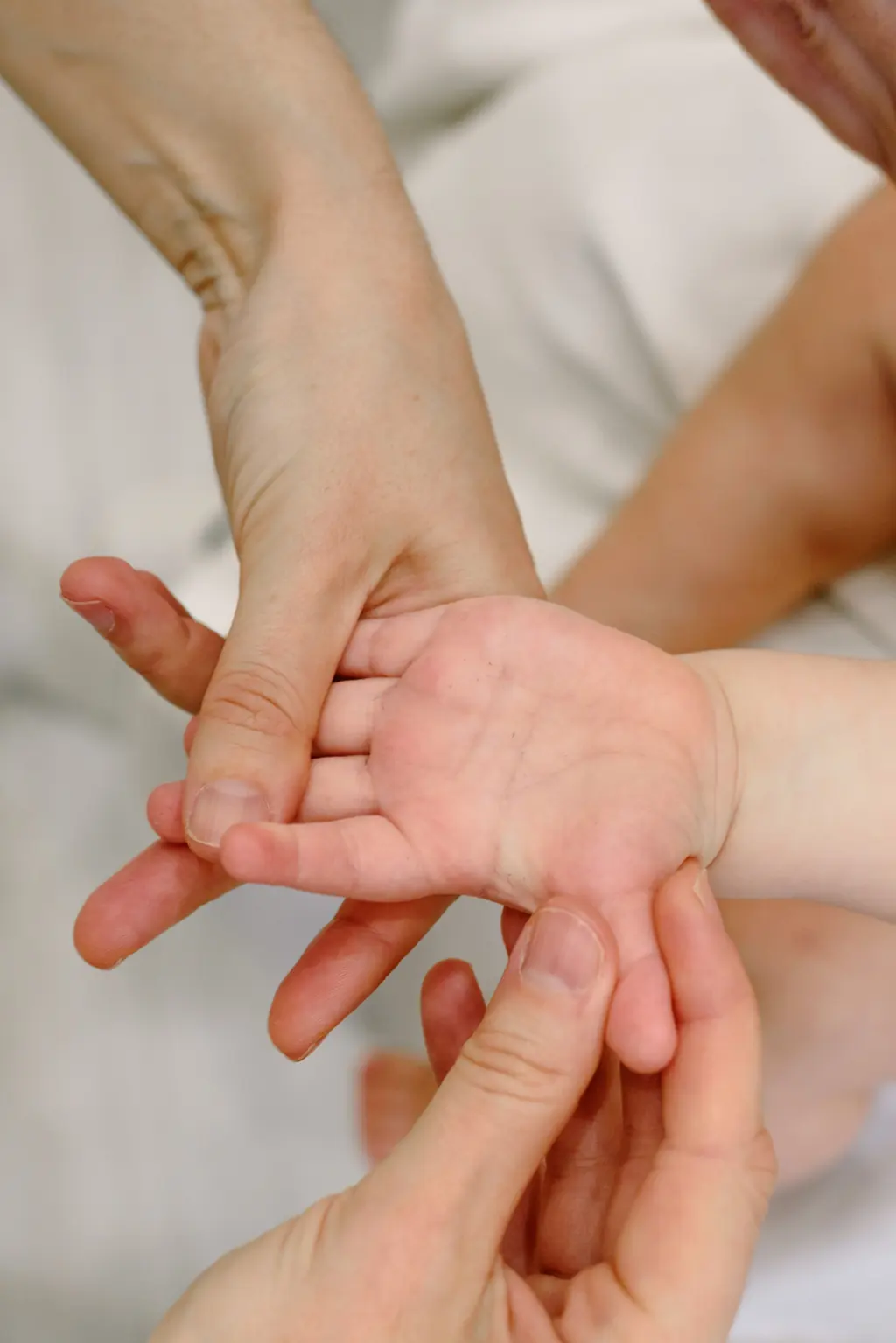 Erwachsene Hände massieren die kleine Hand eines Babys.
