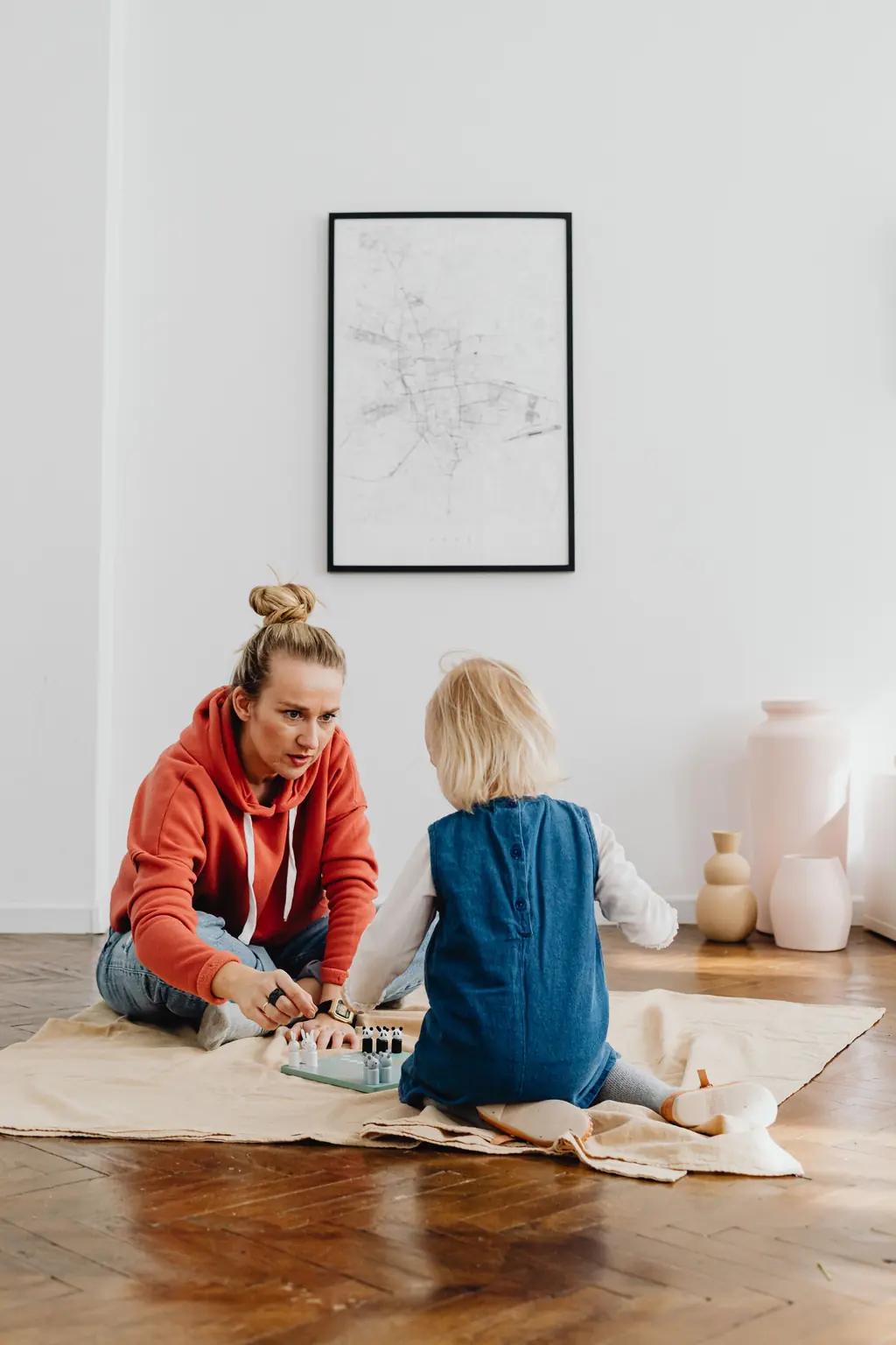 Eine Mutter und ihre kleine Tochter sitzen auf dem Boden und spielen.