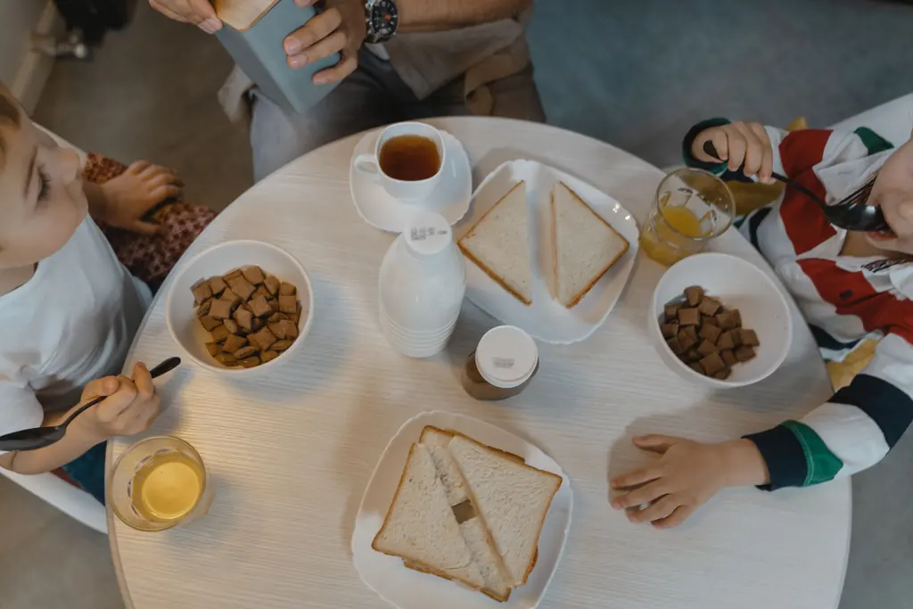 Kinder frühstücken an einem runden Tisch, von oben fotografiert.